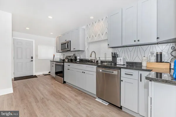 a kitchen with granite countertop white cabinets and white appliances