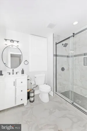 a bathroom with a granite countertop sink mirror vanity and toilet
