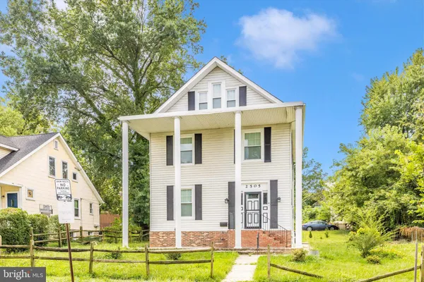 a view of a white house with a swimming pool and lawn chairs under an umbrella
