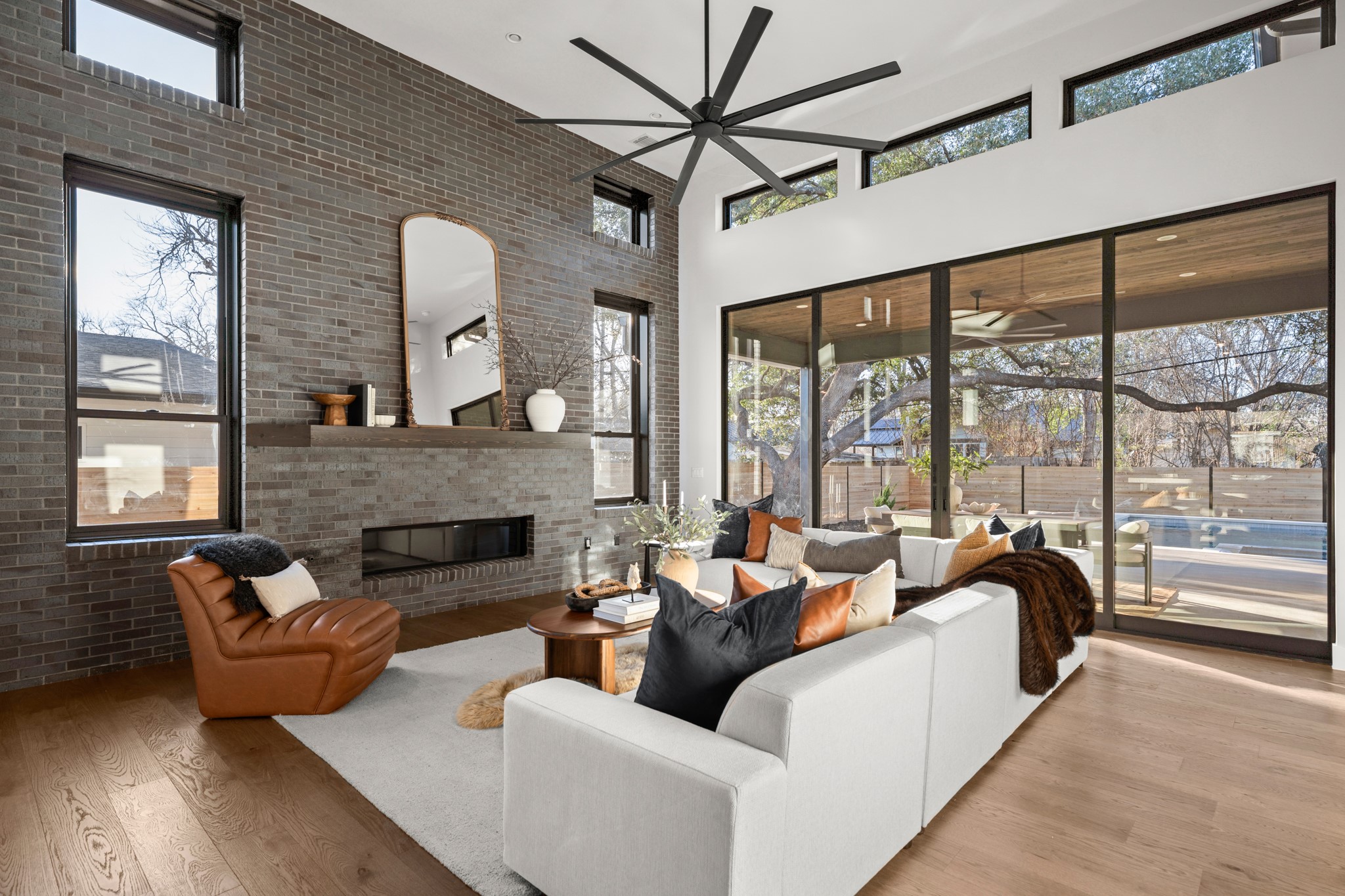 7706 Rutgers Avenue Austin, TX 78757 - Photo 5 of 35 Living room featuring a towering ceiling, brick wall, a brick fireplace, wood finished floors, and healthy amount of natural light