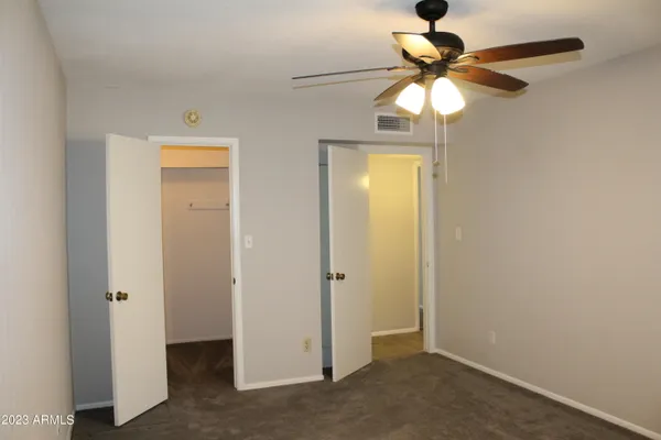 an empty room with closet and a chandelier fan