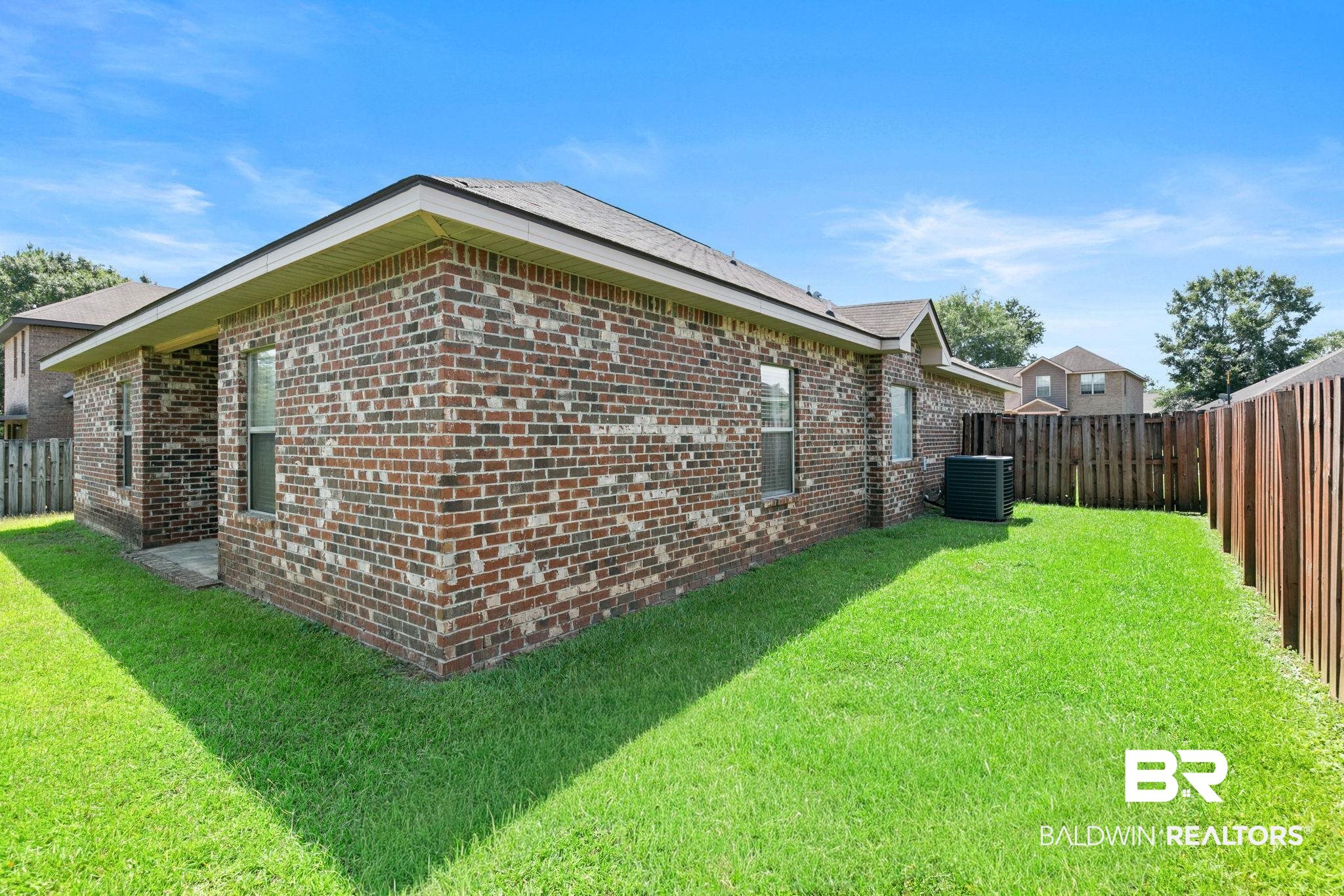 2216 Livingstone Court Mobile, AL 36695 - Photo 45 of 62 Brick exterior with a gabled roofline, multiple windows, and a fully fenced private yard featuring a grass lawn