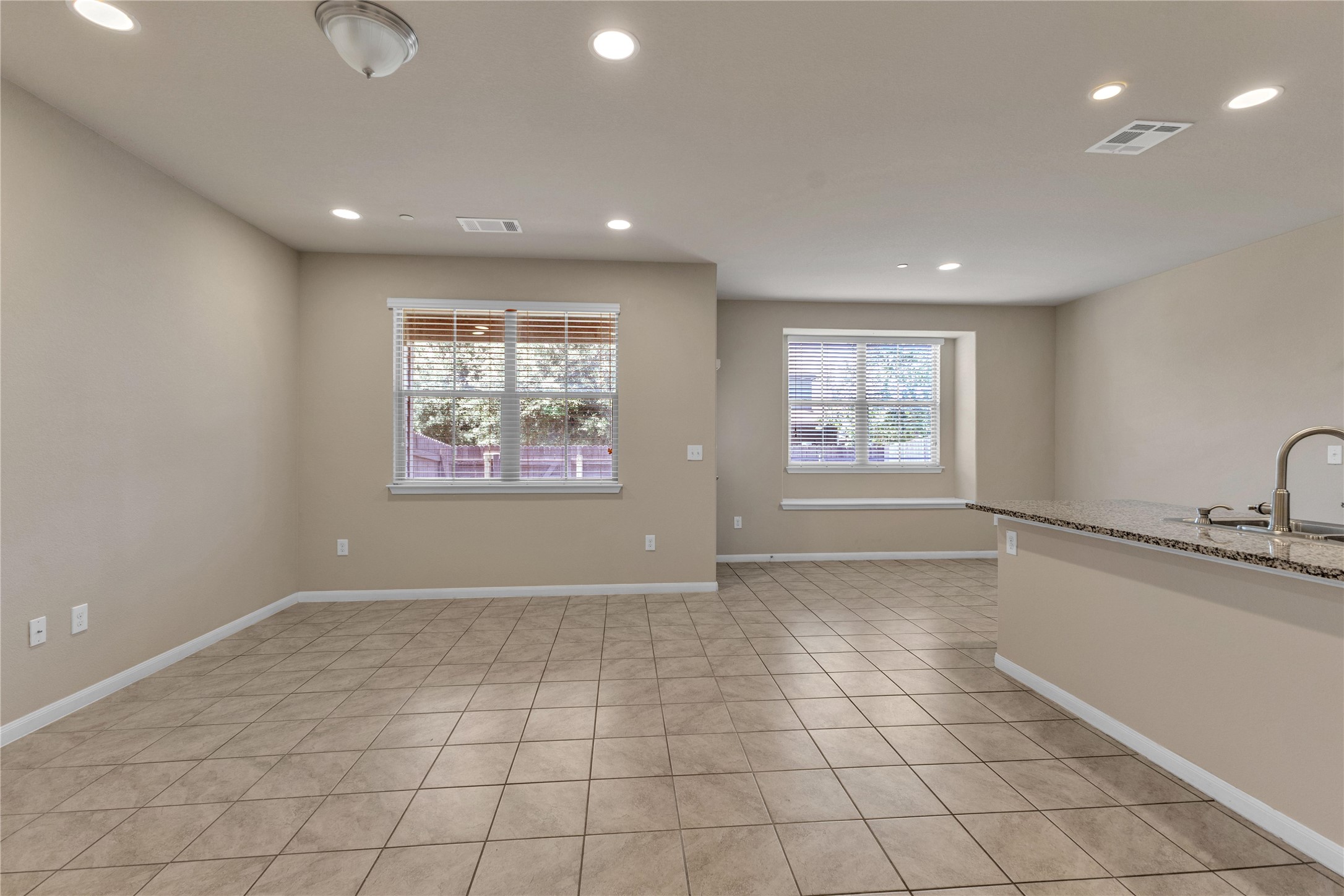 2880 Donnell Drive, Unit 2003 Round Rock, TX 78664 - Photo 8 of 31 Open-concept living area featuring tile flooring, neutral wall tones, recessed lighting, and a breakfast bar with a stone-finish countertop and stainless steel gooseneck faucet