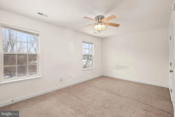 an empty room with windows and fan