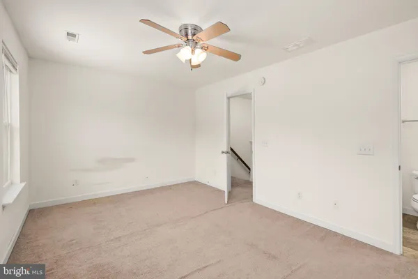 an empty room with a chandelier fan and windows