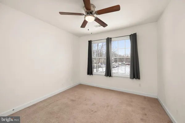 an empty room with windows and ceiling fan