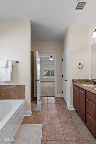 a bathroom with a granite countertop sink a mirror and bathtub