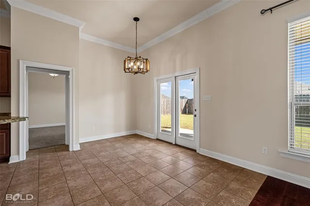 a view of an empty room with window and chandelier