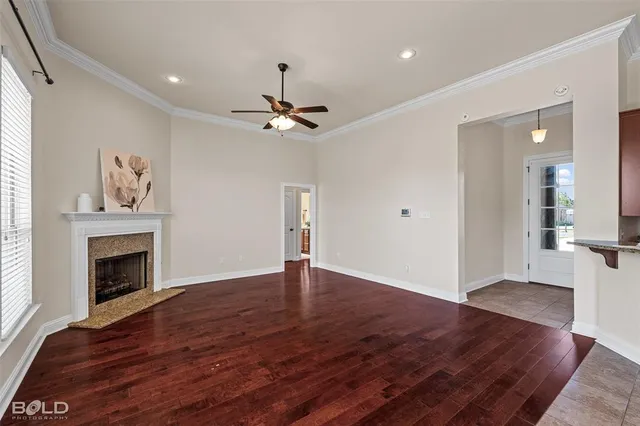 a view of an empty room with wooden floor and a fireplace