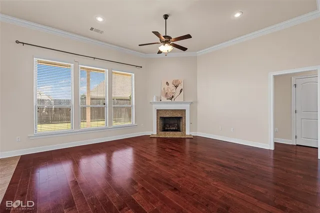 a view of an empty room with wooden floor fireplace and a window