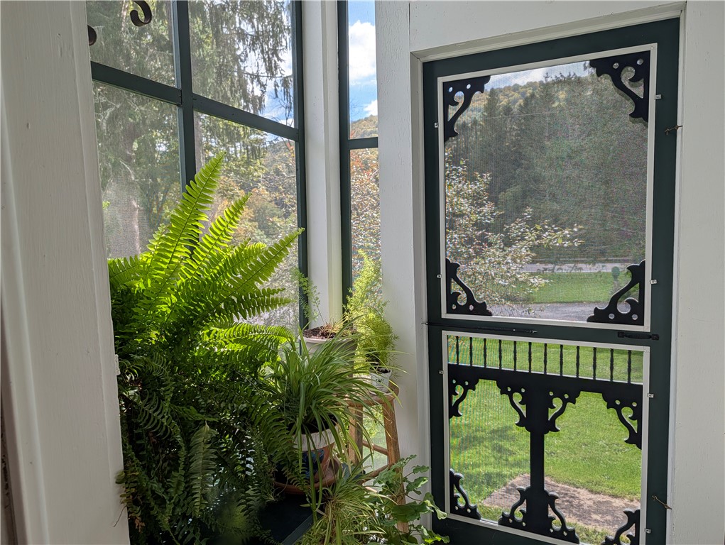 67 Fisk Road Bovina, NY 13753 - Photo 25 of 48 Large windows and a screen door frame picturesque views of the surrounding hills.