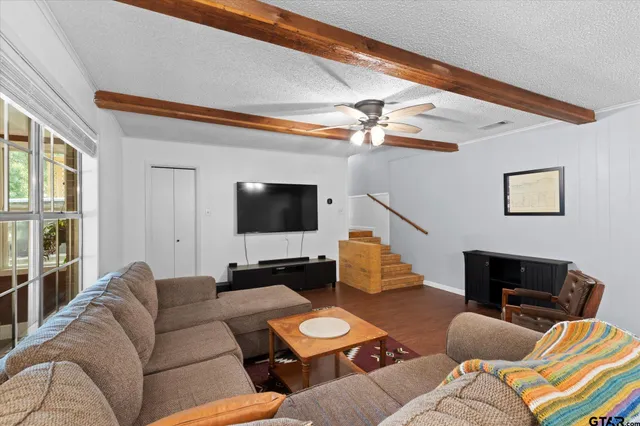 a living room with furniture a flat screen tv and a window