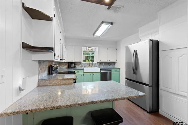 a kitchen with stainless steel appliances granite countertop a refrigerator a stove and a sink