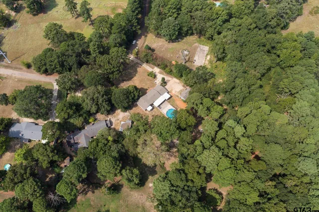 an aerial view of residential house with outdoor space and trees all around