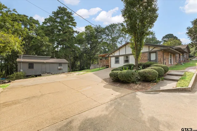 a view of a house with a yard and large tree