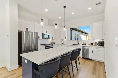 a kitchen with granite countertop a stove a sink dishwasher a refrigerator and a oven with wooden floor