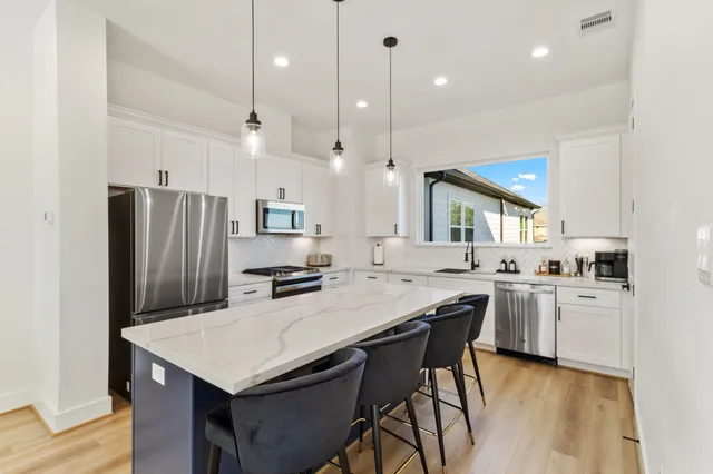 a kitchen with granite countertop a stove a sink dishwasher a refrigerator and a oven with wooden floor