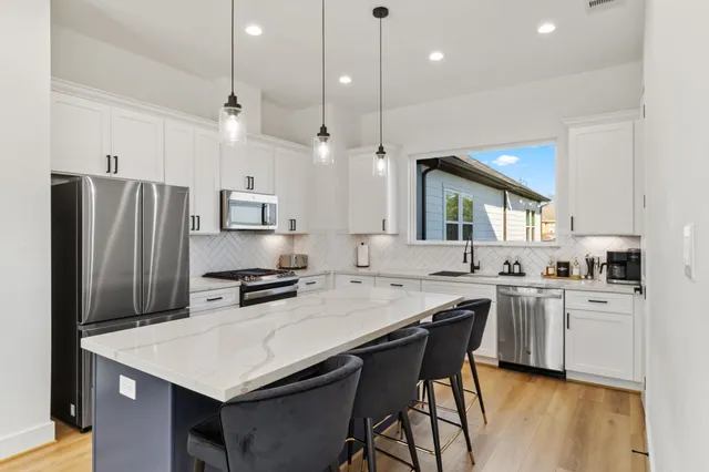 a kitchen with a stove a refrigerator a sink and chairs