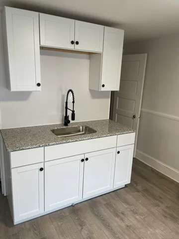 a kitchen with granite countertop white cabinets and a sink