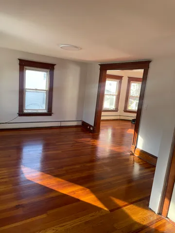 a view of an empty room with wooden floor and a window