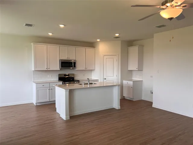 a kitchen with granite countertop a sink cabinets and wooden floor