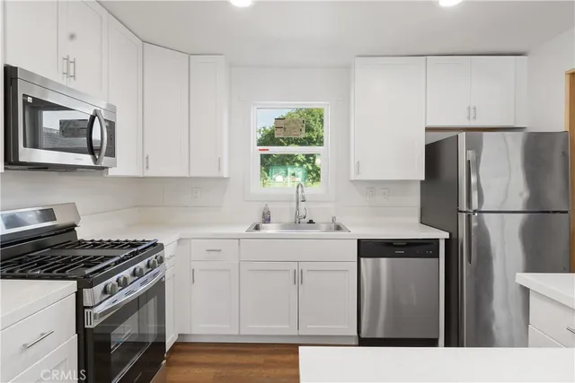 a kitchen with stainless steel appliances white cabinets and a stove top oven