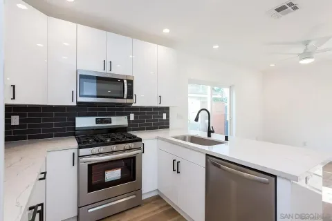a kitchen with sink a microwave a stove and cabinets