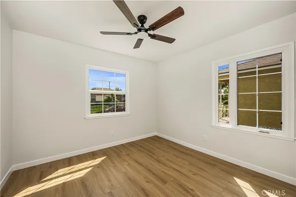 a view of an empty room with a window and wooden floor