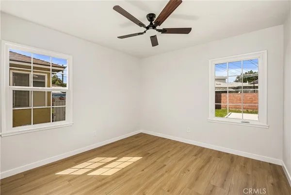 a view of empty room with wooden floor and ceiling fan