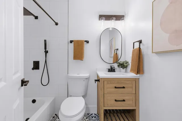 a bathroom with a toilet sink vanity tub and mirror