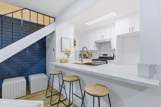 a kitchen with stainless steel appliances granite countertop a refrigerator a stove a sink and white cabinets with wooden floor