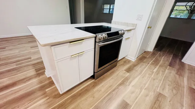 a kitchen with a stove and a wooden floor