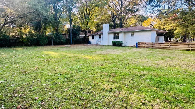 a view of house with yard and trees in the background