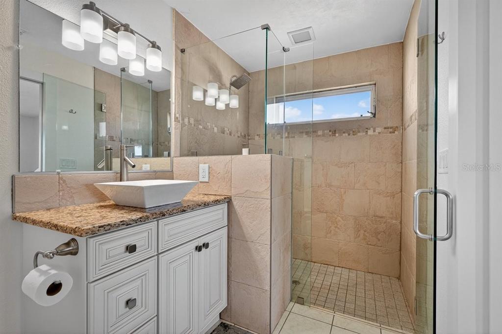 450 Lambert Avenue Flagler Beach, FL 32136 - Photo 21 of 41 a bathroom with a granite countertop sink a mirror and shower