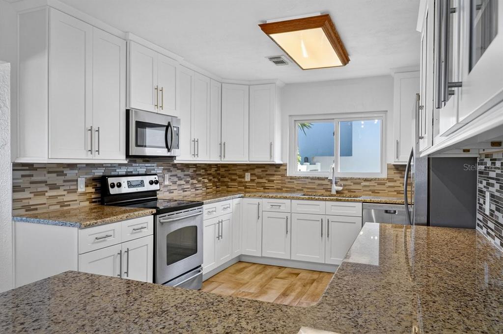 450 Lambert Avenue Flagler Beach, FL 32136 - Photo 30 of 41 a kitchen with stainless steel appliances granite countertop a stove top oven a sink and white cabinets
