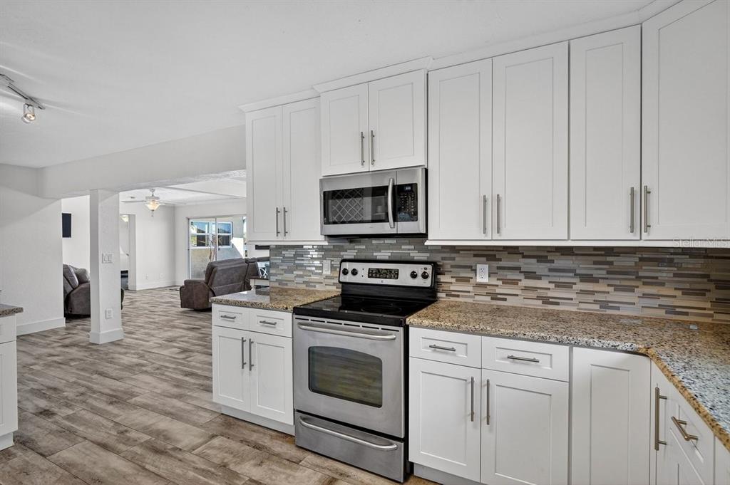 450 Lambert Avenue Flagler Beach, FL 32136 - Photo 33 of 41 a kitchen with granite countertop white cabinets white stainless steel appliances with a sink and dishwasher