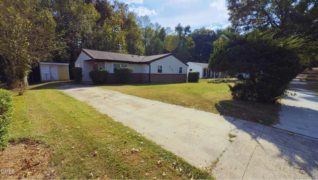 a front view of house with yard and trees in the background