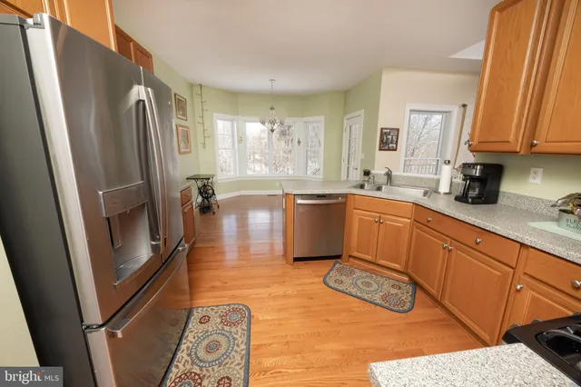 a kitchen with stainless steel appliances granite countertop a refrigerator a sink a stove and white cabinets