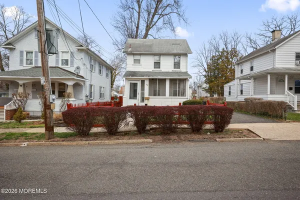 a front view of a building with a garden and parking space