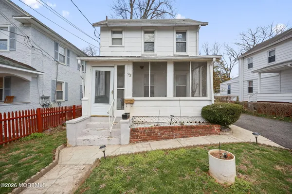 a view of a white house with a yard potted plants and a bench