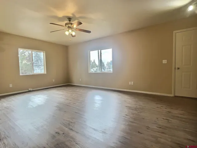 an empty room with wooden floor and windows