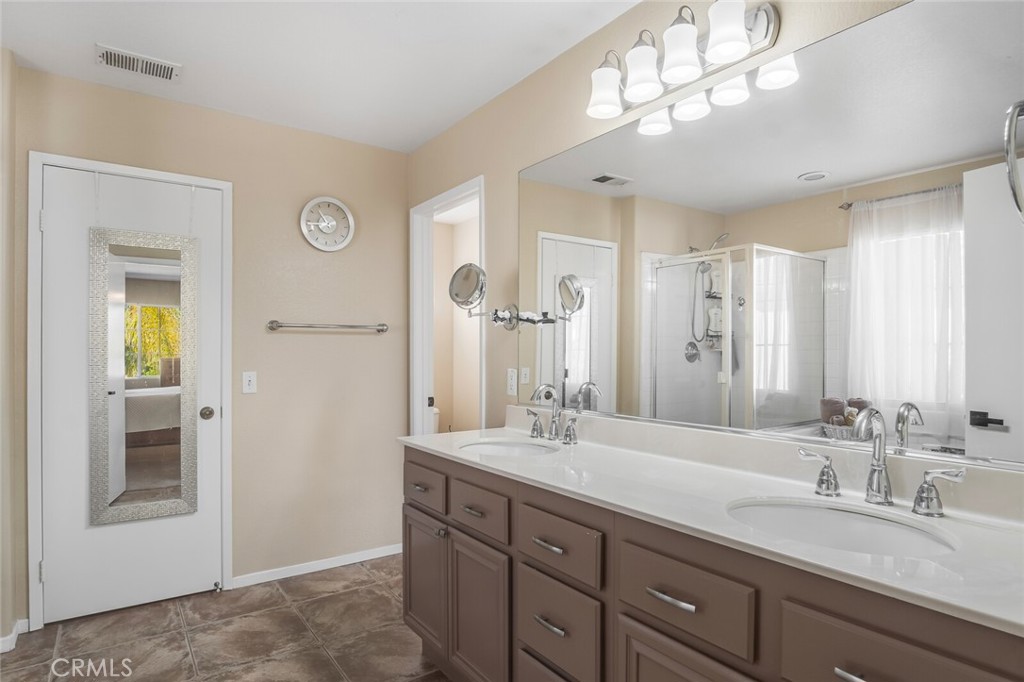4330 Forest Ranch Way Oceanside, CA 92057 - Photo 24 of 51 The ensuite bath feels like a private spa, with dual sinks, ample drawers and cabinets, extra large mirror, upgraded tile flooring and elevated lighting. The walk-in closet is designed for comfort and function.