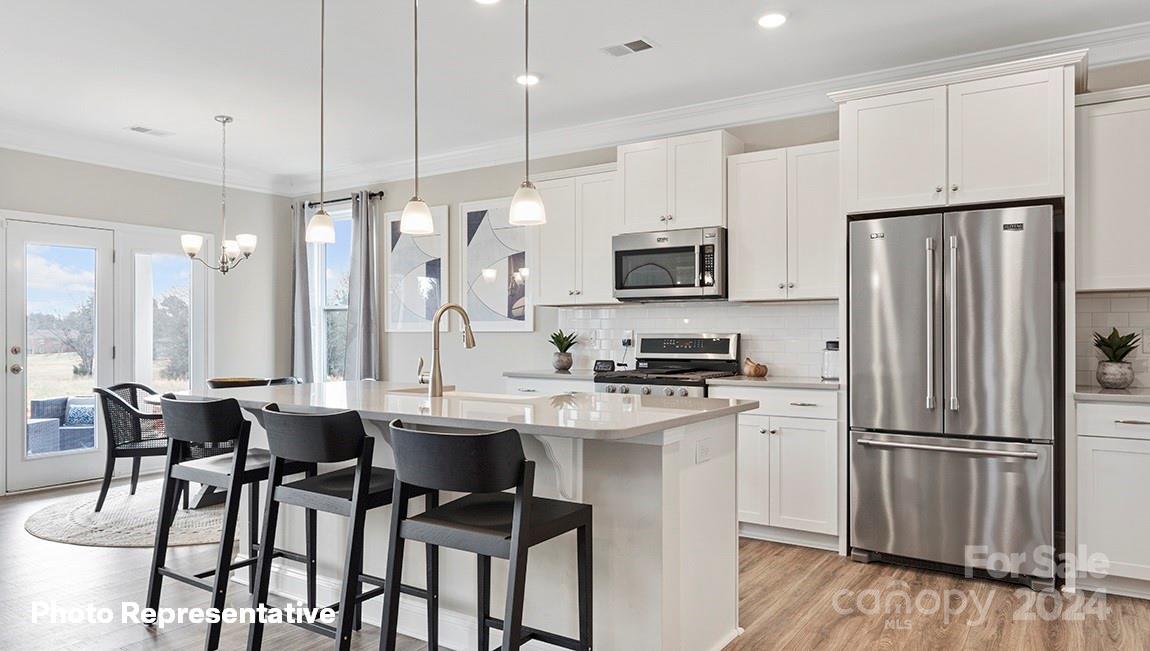 308 Streamwood Road Troutman, NC 28166 - Photo 11 of 39 a kitchen with stainless steel appliances a dining table chairs refrigerator and microwave