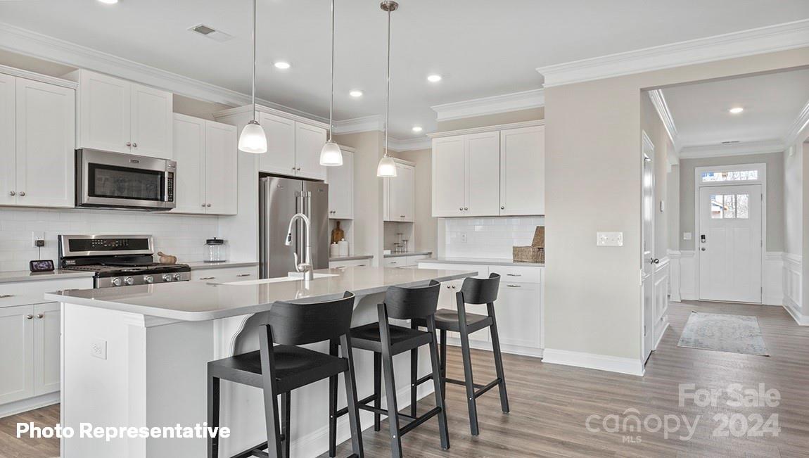 308 Streamwood Road Troutman, NC 28166 - Photo 14 of 39 a kitchen with stainless steel appliances kitchen island granite countertop a stove a refrigerator a sink a dining table and chairs with wooden floor