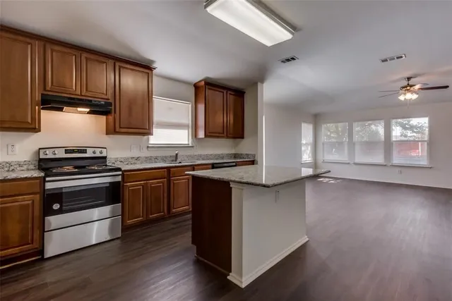 a kitchen with granite countertop wooden floors a stove and a microwave