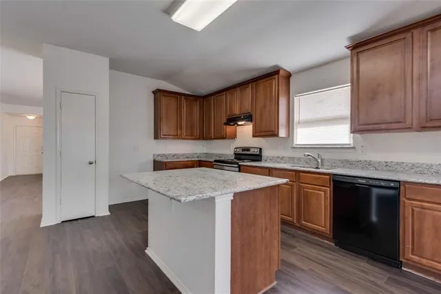 a kitchen with stainless steel appliances granite countertop wooden cabinets a sink and dishwasher with wooden floor
