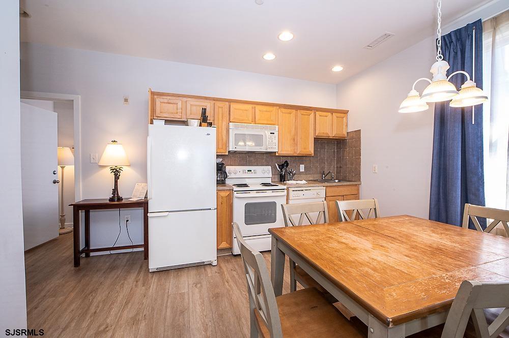 1001 Little Atlantic Avenue, Unit 373 Ocean City, NJ 08226 - Photo 5 of 27 a kitchen with kitchen island a stove a refrigerator and a dining table with wooden floor