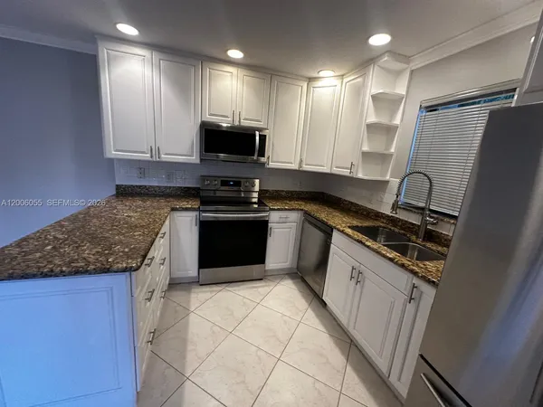 a kitchen with stainless steel appliances granite countertop a stove a sink and a microwave