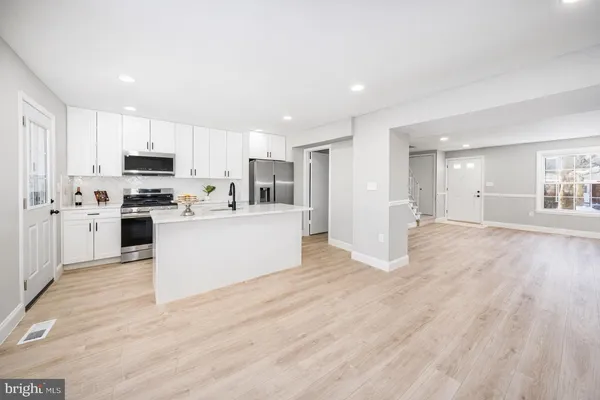a view of kitchen with kitchen island a sink a stove a microwave and white cabinets