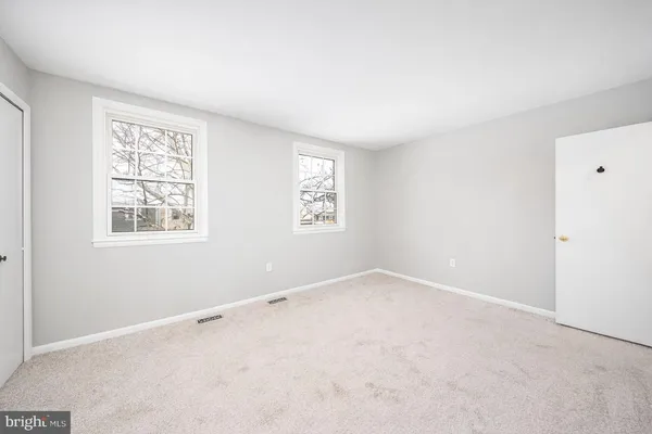 a spacious bedroom with a bed a mirror and a large window